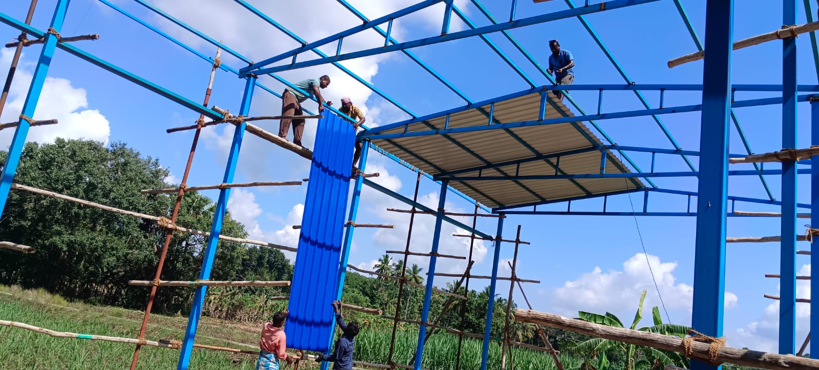 Workers installing blue panels on the shed